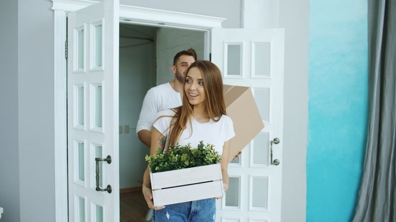 Blue Jean mover carrying a sofa through a doorway